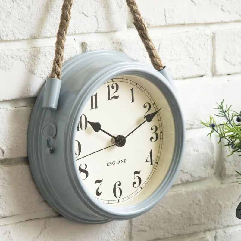 Horloge murale ronde grise suspendue corde jute mur briques blanches