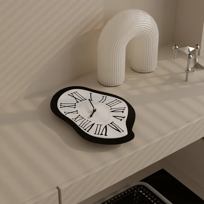 Horloge design forme fondue noir blanc chiffres romains posée sur bureau