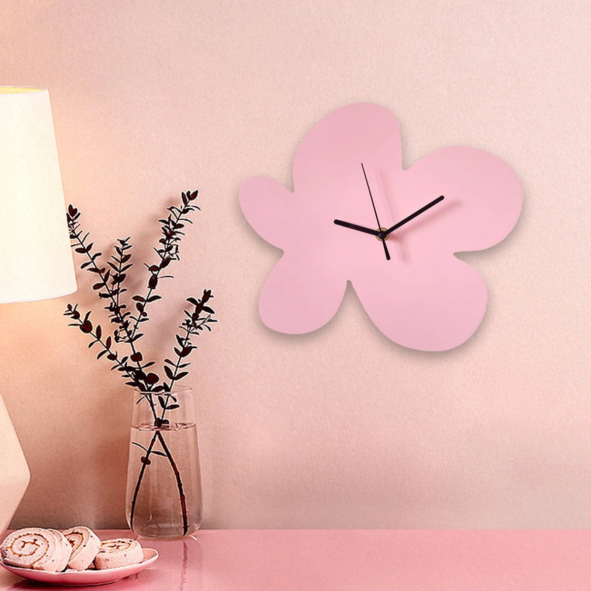 Horloge murale fleur rose sans chiffres aiguilles noires mise en situation chambre